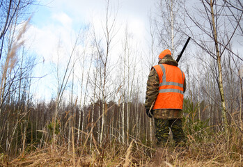 Hunter while hunting wild animals. Hunters track down a wild boar or elk in the forest. Hunter during hunting in forest. Hunters with gun and rifle on hunting in the fall season.