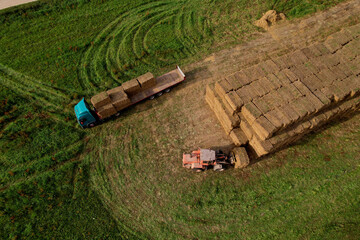 Hay Trailer with round bales. Front end loader unloading round bales. Store hay at farm. Hay rolls...