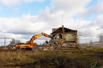 Excavator during demolition the house in the rural. Renovation old home and construction project. Backhoe demolishes building. Tearing Down a Houses. Destroy concrete for recycling and reuse.