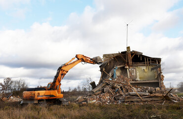 Excavator during demolition the house in the rural. Renovation old home and construction project. Backhoe demolishes building. Tearing Down a Houses. Destroy concrete for recycling and reuse.