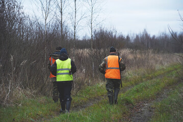 Hunter during hunting in forest. Hunter while hunting wild animals. Hunters with gun and rifle on hunting in the fall season. Hunters track down a wild boar or elk in the forest.