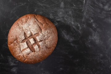 Loaf of rye bread on a black kitchen table, top view