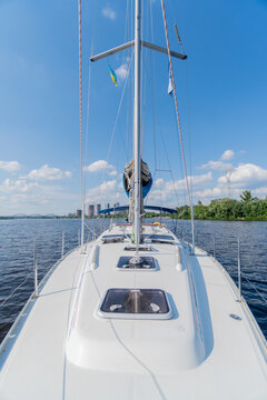 Modern luxury sailing yacht stands on the river. White hull of the yacht with close hatches. Bluer calm sea. Vertical photo
