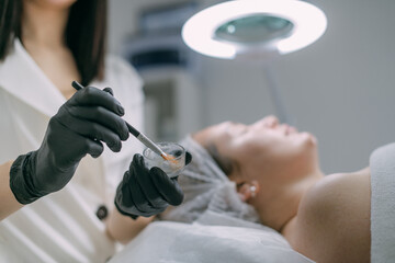 Cosmetologist and dermatologist makes a moisturizing, rejuvenating woman lying patient in a beauty salon.