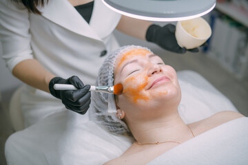 Naklejka premium Cosmetologist and dermatologist makes a moisturizing, rejuvenating woman lying patient in a beauty salon.