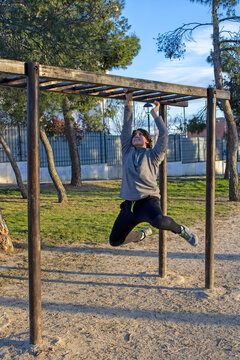 Teenage doing exercise in a park with parallel bars
