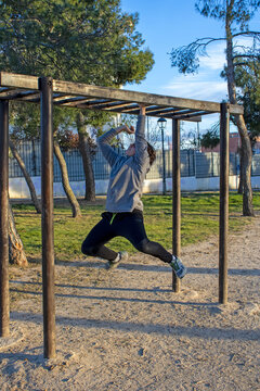 Teenage doing exercise in a park with parallel bars