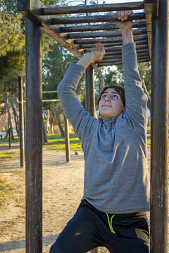 Teenage doing exercise in a park with parallel bars