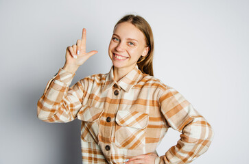 the blonde girl holds her finger up on a white background. the concept of advertising and space for inscription