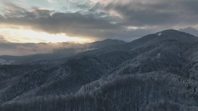 Winter mountain range peak covered in snow sunrise cloudy sky aerial view