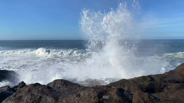 Huge ocean wave crashes into the air after smashing into rocky Oregon coastline at high tide.
