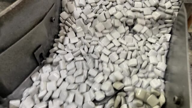 close up of mass deburring process, vibrating with ceramic chips or abrasive stones, removal of burrs from metal parts