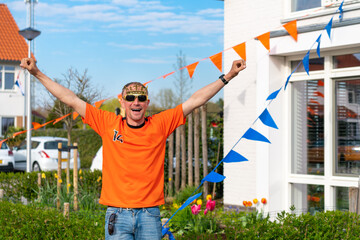 Dutchman celebrating kings day on the road during a street party dressed in orange in Holland the Netherlands. Koningsdag is a traditional festival to celebrate the Dutch royal family. Dutch flag.