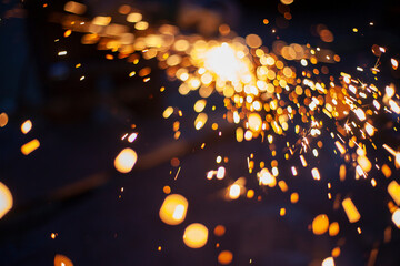 Sparks from grinding metal. Steel processing in workshop. Lights in dark. Production of parts....