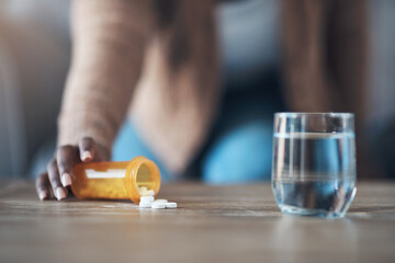 Time for my dose of painkillers. Cropped shot of an unrecognizable woman sitting alone and taking pills out of a pill bottle in her living room.