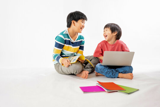 Portrait of Happy asian boys, Brother on floor with laptop and books isolated on white background, Education and learning with technology concept