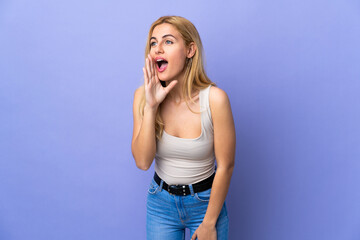 Young Uruguayan blonde woman over isolated background shouting with mouth wide open to the side