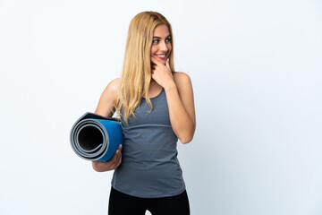 Young sport woman going to yoga classes while holding a mat over isolated white background thinking an idea and looking side