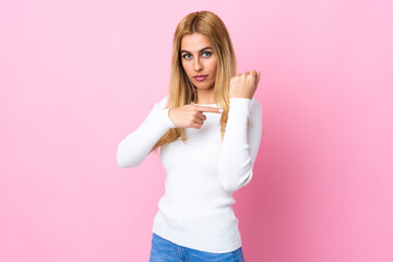 Young Uruguayan blonde woman over isolated pink background making the gesture of being late