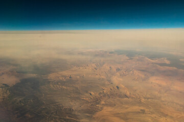 Aerial view of the deserts in the western United States featuring Canyons, rock formations, clouds and parceled farmland