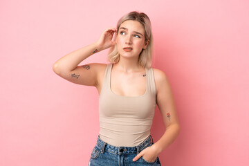 Young caucasian woman isolated on pink background having doubts