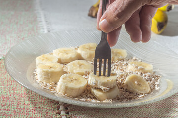 flaked oats and sliced banana, on a plate that is on a table with natural light,copy space in several parts