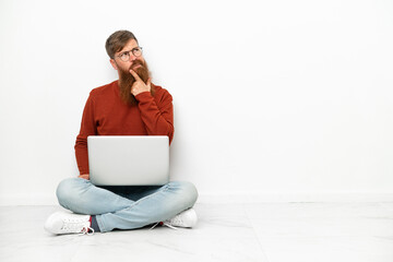 Young reddish caucasian man with laptop isolated on white background having doubts and thinking