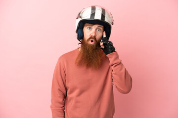 Young reddish caucasian man with a motorcycle helmet isolated on pink background thinking an idea
