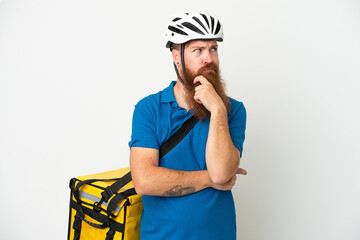 Young reddish caucasian man with thermal backpack isolate don white background having doubts and thinking