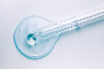 Liquid cool blue gel or serum with dropper on gray background