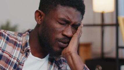 Close-up sad face of african american man sitting at home looks pensive thinks over life concerns or unrequited love, suffers from unfair situation. Problem, break up, depressed feeling bad annoyed