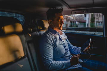 One man young adult caucasian manager or business director sitting on the back seat of the car while having online call conference using digital tablet to arrange business real people copy space