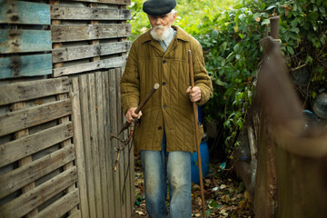 An old man near the barn. An old man in the garden. An elderly man in Russia.