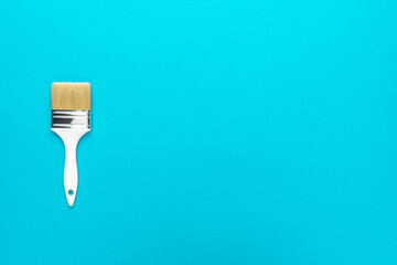 Paint brush on the turquoise blue background. Minimalist photo of white brush with copy space. Flat lay top-down composition of white brush.