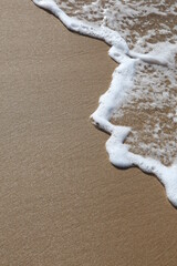 A wave rolls up the sand at the beach with Copyspace