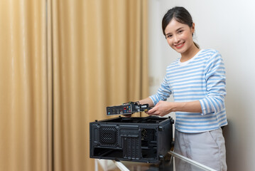 Beautiful Asian woman putting a computer gamer motherboard into a black case.