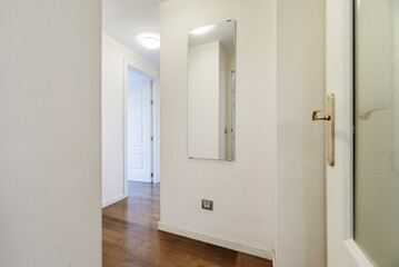 Entrance to a residential home with nook and cranny hallways, white painted walls and parquet flooring