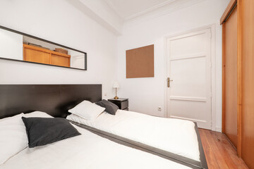 Fototapeta na wymiar Bedroom with double beds, dark wood headboard and built-in wardrobe with cherry wood sliding doors