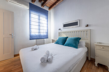 Bedroom with king size bed with blue velvet cushions and white lacquered wooden bed furniture