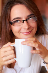 Excited for the day ahead. A young woman drinking her coffee with a thoughtful look.