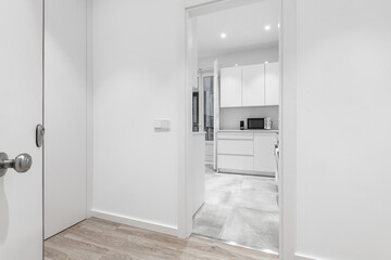 Entrance of a vacation rental home with white kitchen cabinets and wooden floors with white painted walls