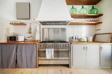 beautiful built-in kitchen with wooden worktop, gas stove with ovens and large extractor hood with...