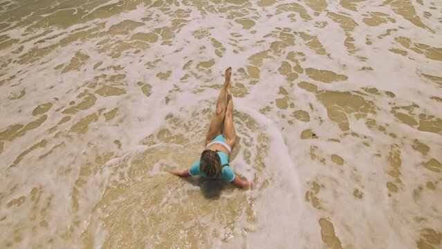 Crazy madwoman daring funny woman lying on shallow water sea. Top view happy slightly tipsy woman enjoying her vacation on a tropical island. Smiling girl funny posing. Concept summer holidays