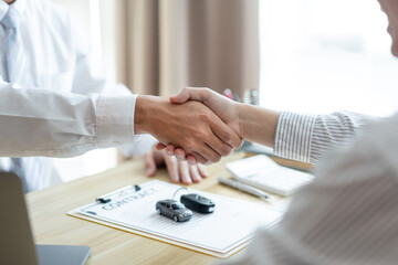 Insurance concept the car broker shaking hand with his customer after finishing dealing the contract