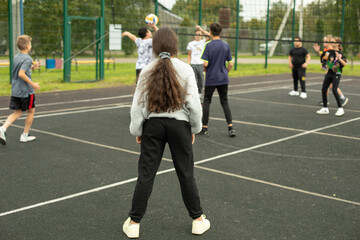 Fototapeta premium Children play volleyball. Playing ball on court. Sports activity.