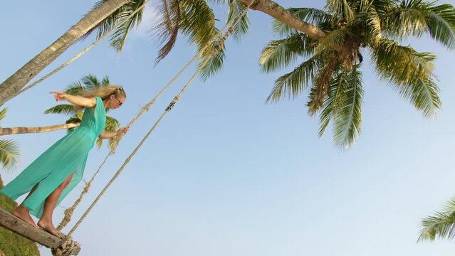 Seductive woman swinging on a swing on a tropical beach, on shores of the turquoise sea. Concept travel, walks, rest in sea, tropical resort coastline relaxation traveling tourism summer holidays