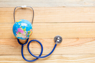 Stethoscope wrapped around globe on wooden floor background. Save the wold, Global healthcare and...
