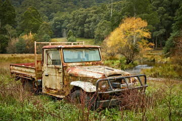 Old vehicle abandoned in the Australia bush near a stream trees and grassland
