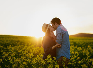 Fototapeta premium Sharing a magical moment together. Shot of an affectionate young couple sharing a kiss at sunset.