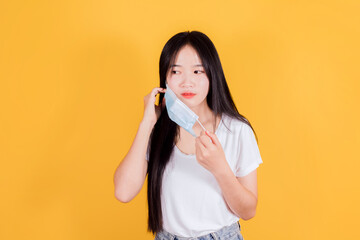 Asian woman wearing medical face mask to protect Covid-19 (Coronavirus) on yellow background, health and medicine concept